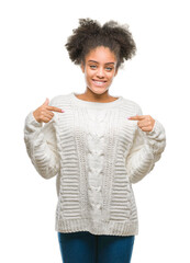 Young afro american woman wearing winter sweater over isolated background looking confident with smile on face, pointing oneself with fingers proud and happy.