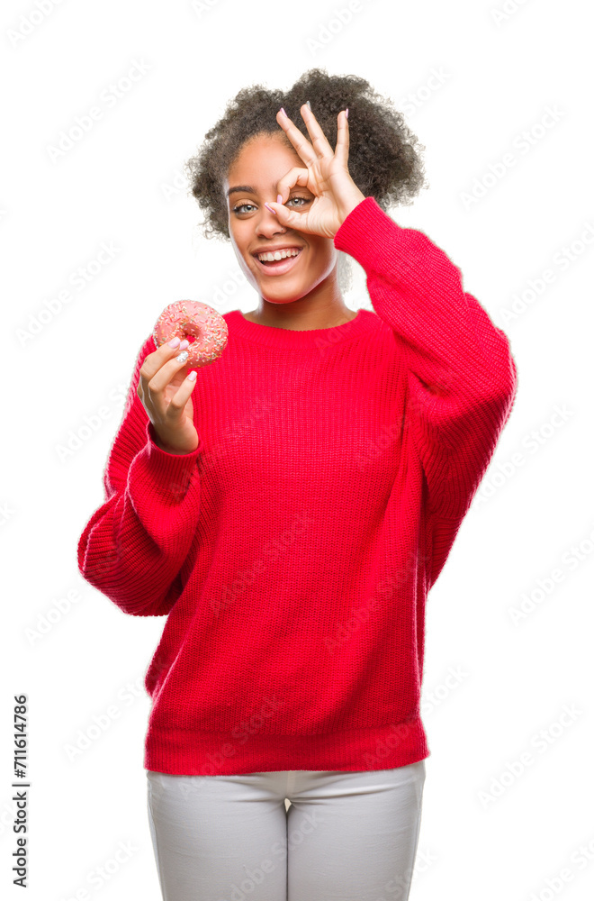 Canvas Prints Young afro american woman eating donut over isolated background with happy face smiling doing ok sign with hand on eye looking through fingers