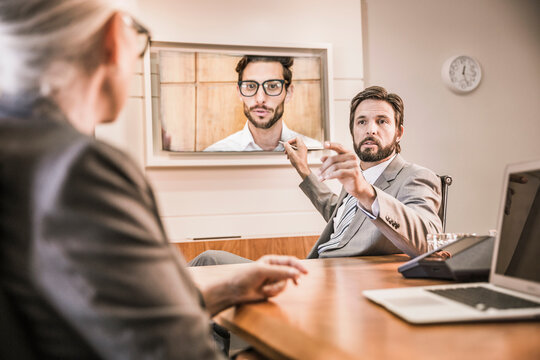 Two colleagues having a teams meeting in a conference room with third colleague