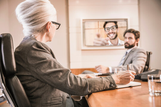 Two colleagues having a teams meeting in a conference room with third colleague