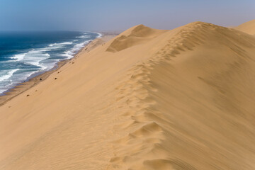 Fototapeta na wymiar footprints on dune edge at Atlantic shore near Sandwich Harbour, Namibia