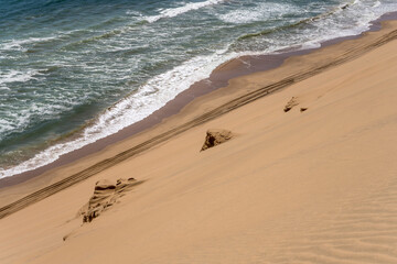 tyre tracks on shore with dune slope and Atlantic waves near Sandwich Harbour, Namibia © hal_pand_108