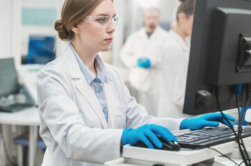 female scientist working in a modern equipped computer laboratory analyzes blood samples and...