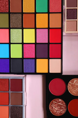 Various colorful eyeshadow palettes on bright pink background. Flat lay.