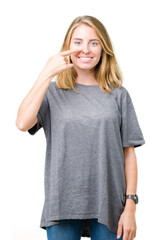 Beautiful young woman wearing oversize casual t-shirt over isolated background Pointing with hand finger to face and nose, smiling cheerful