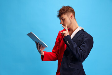 Young attractive male model with female and male appearance focused looking at tablet checking...