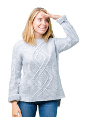 Beautiful young woman wearing winter sweater over isolated background very happy and smiling looking far away with hand over head. Searching concept.