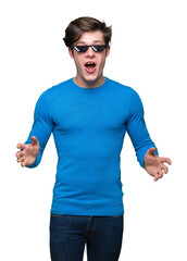 Young man wearing funny thug life glasses over isolated background afraid and shocked with surprise...
