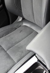 Dents and scuffs on the leather surface of a car seat trimmed with leather and alcantara
