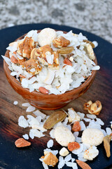 closeup the mix snack food drilled rice coconut,raisins,peanut ,sesame seeds in the wooden bowl on the brown background.