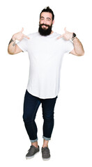 Young hipster man with long hair and beard wearing casual white t-shirt looking confident with smile on face, pointing oneself with fingers proud and happy.