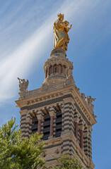 Fototapeta na wymiar Golden blessed Mary with Jesus child on top of the tower of Cathedral of Notre-Dame de la Garde in Marseille, France