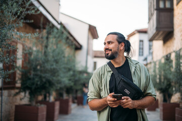 A male tourist with a phone in his hands on the street of the old town.