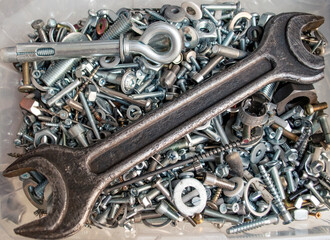 Box with lots of screws and bolts and other fasteners. Large wrench in a box with screws....