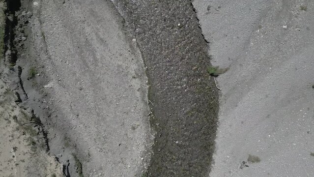 Drone footage, top down view, of a small river winding towards a lake