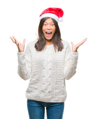 Obraz na płótnie Canvas Young asian woman wearing christmas hat over isolated background celebrating crazy and amazed for success with arms raised and open eyes screaming excited. Winner concept
