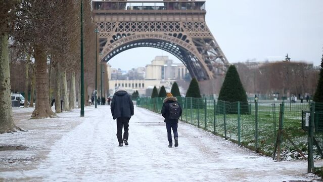 People passing by the Eiffel tower in Paris on a snowy day