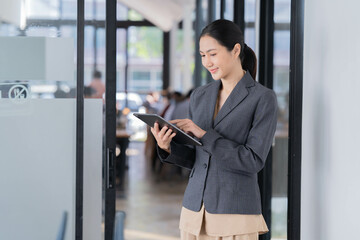 Sharing good business news. Attractive young businesswoman talking on the mobile phone and smiling while sitting at her working place in office and looking at laptop PC.