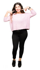 Fototapeta premium Young beautiful woman wearing pink sweater smiling confident showing and pointing with fingers teeth and mouth. Health concept.