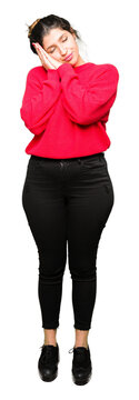 Young beautiful woman wearing red sweater and bun sleeping tired dreaming and posing with hands together while smiling with closed eyes.