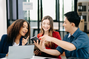 Happy businesspeople while collaborating on a new project in an office. Group of diverse businesspeople using a laptop and tablet .