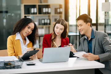 Office colleagues have a casual discussion. During a meeting in a conference room, a group of business teem sit in the room new startup project..