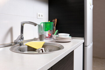 Work area in home kitchen with refrigerator and sink.