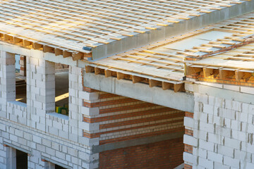 A new wooden roof structure lining a house in the city. Industrial roofing system with wooden beams, ceilings and tiles. Roofing works.