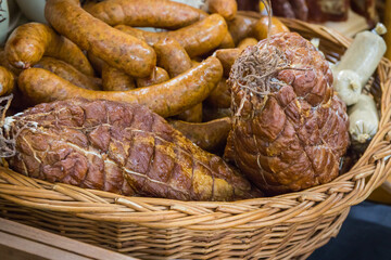 Fresh prepared smoked hams with spices in wicker basket on market stall