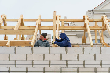 Two carpenters are working on a wooden roof structure at a construction site. Industrial roofing...