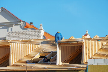 Two carpenters are working on a wooden roof structure at a construction site. Industrial roofing...