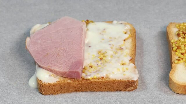 Preparing process of Croque monsieur and croque madame, grilled sandwiches with sliced ham, melted cheese, dijon mustard and poached egg on  bechamel sauce.