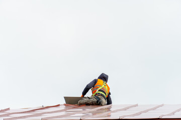 A carpenter is working on a wooden roof structure at a construction site. Industrial roofing system with wooden beams, beams and tiles. Roofing works.