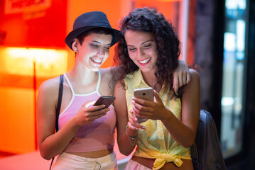 Two young women having fun in the city at summer night. - 711676557