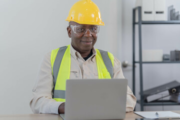 Professional of man architect industrial engineer Standing in the office, foreman in helmet using laptop working with new construction project architectural plan.