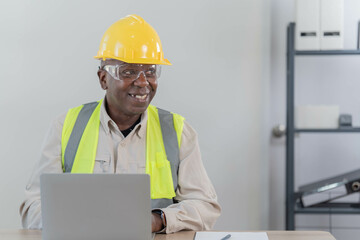 Professional of man architect industrial engineer Standing in the office, foreman in helmet using laptop working with new construction project architectural plan.