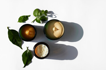Body care.  Skincare cosmetics.  A different containers of  a natural herbal moisturising products scrub, peeling, green tea tree lotion and chea butter, top view, white background