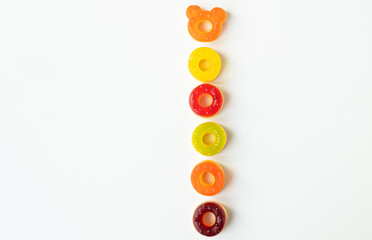 A vertical arrangement of colorful gummy candies on a white background. One candy is shaped like a...
