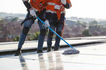Professional electrical engineers working on the residential rooftop to clean up the dusty solar panels.