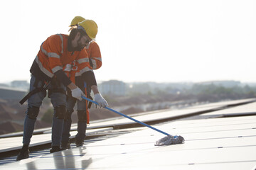 Professional electrical engineers working on the residential rooftop to clean up the dusty solar...