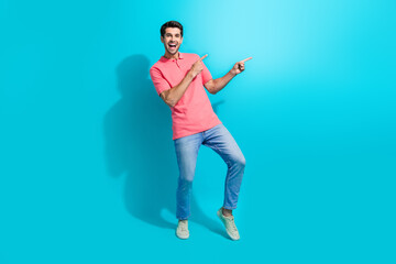 Full body length photo of young crazy overjoyed guy pointing fingers empty space surprised prices isolated on aquamarine color background