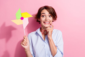 Photo of creative cheerful lady finger touch lips toothy smile hold windmill spinner isolated on...