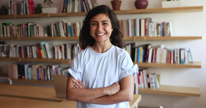 Pretty Indian businesswoman, library female worker or enthusiastic teacher standing in modern workplace. Successful corporate employee, qualified tutor, professional occupation person indoor portrait