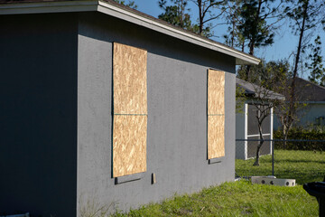 Plywood mounted as storm shutters for hurricane protection of house windows. Protective measures...