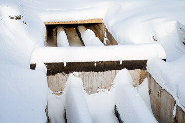 Repair of the pipeline in winter, frozen pipes lie under a layer of snow, a concrete trench of the...