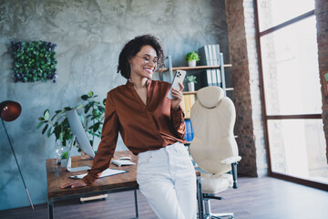 Photo of cheerful chief director lady hold use smart phone chatting loft interior workstation indoors