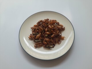 salted squid (cumi asin) stir fried food on a plate top view on a white background. concept background of seafood, healthy food, food recipes, dish, cuisine, gourmet, culinary, lifestyle, cooking