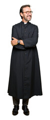 Middle age priest man wearing catholic robe smiling looking side and staring away thinking.