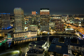 Fototapeta premium View from above of brightly illuminated high skyscraper buildings in downtown district of Tampa city in Florida, USA. American megapolis with business financial district at night