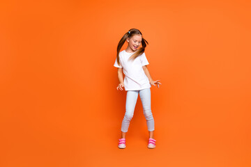 Full body photo of overjoyed positive girl dancing partying empty space ad isolated on orange color...